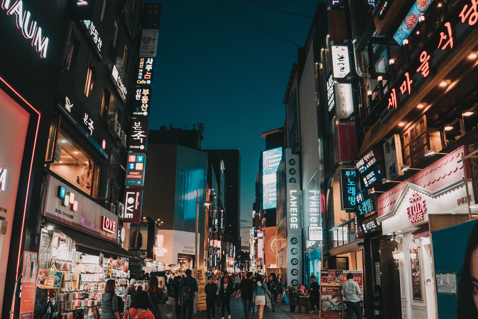 Imagem noturna de uma rua comercial movimentada em Seul
