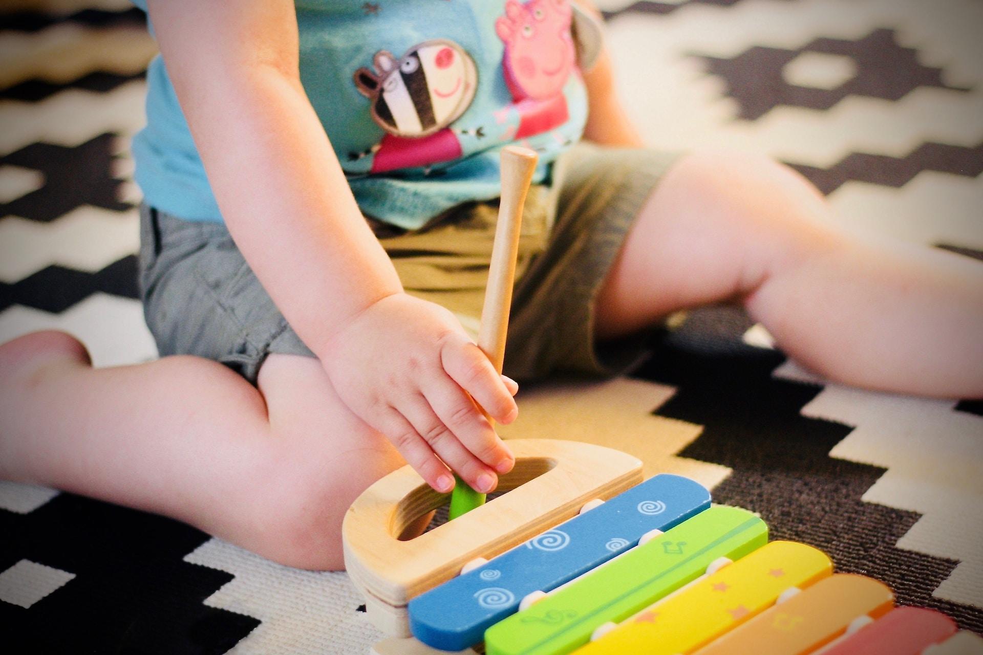 criança sentada em um tapete jogando com um brinquedo