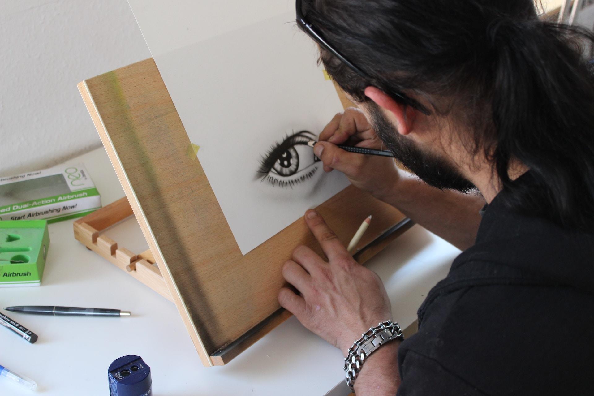 Homem desenhando um olho com bastante detalhes.