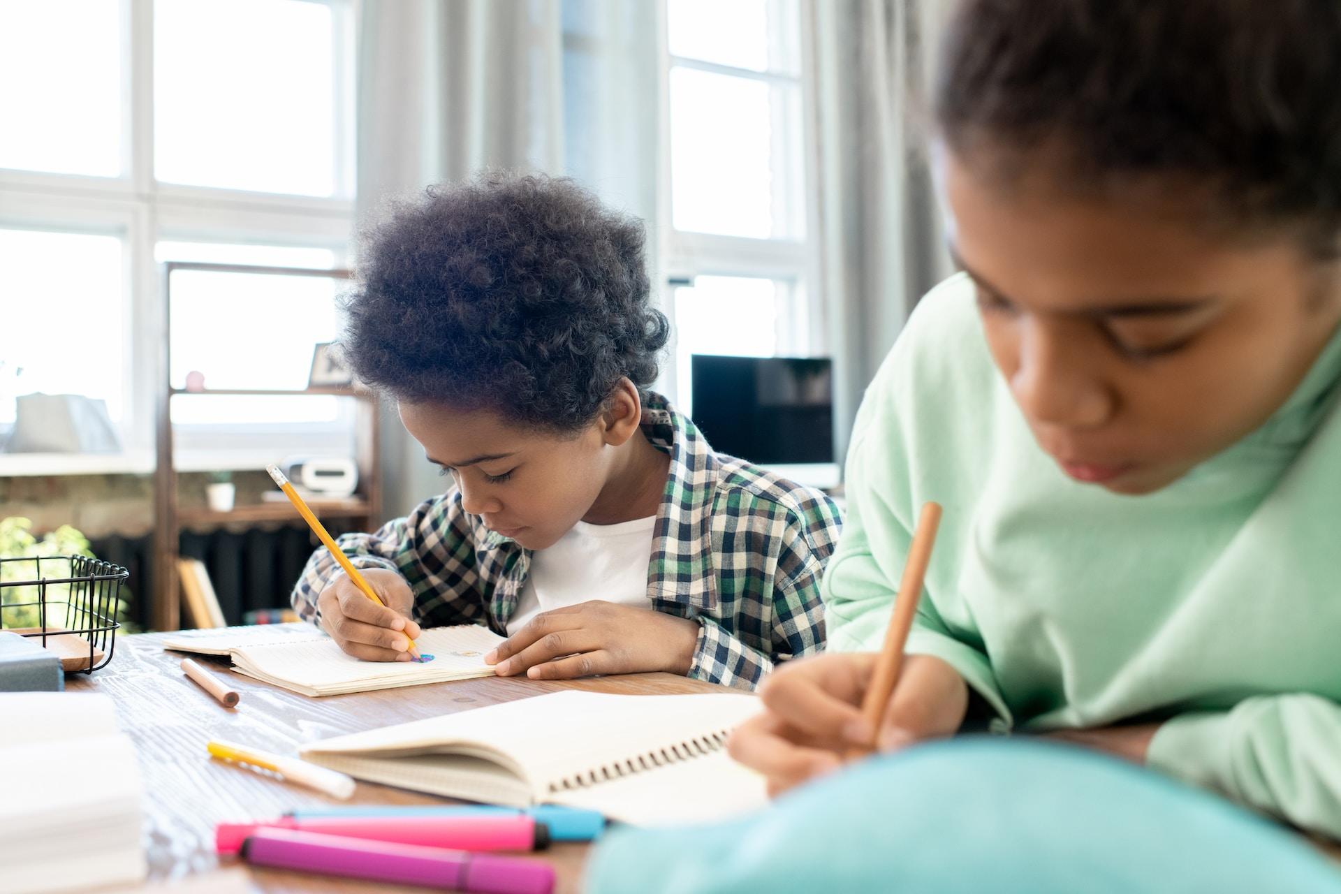 duas crianças estudando em uma mesa