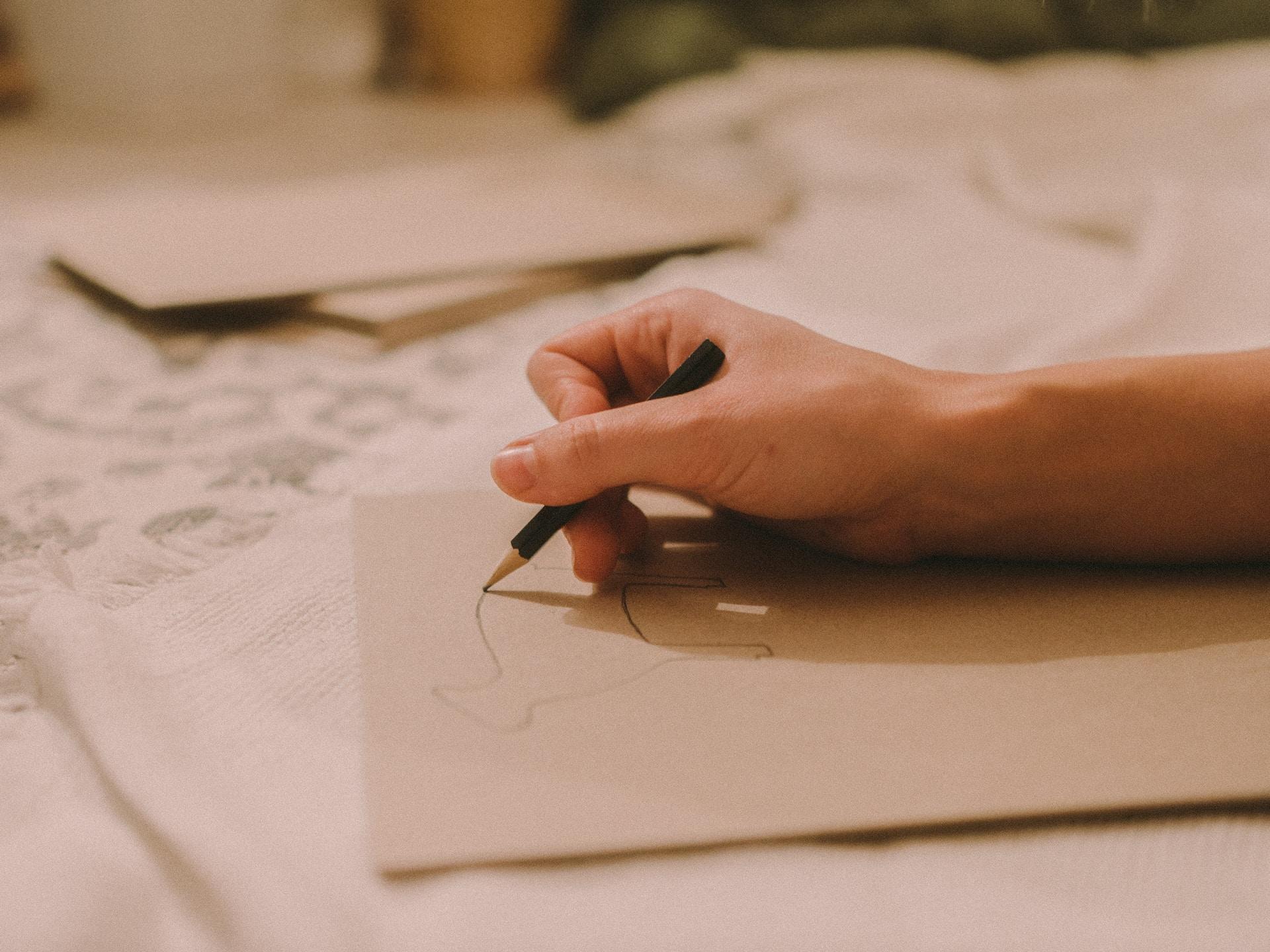 Mãos desenhando um contorno de um animal.