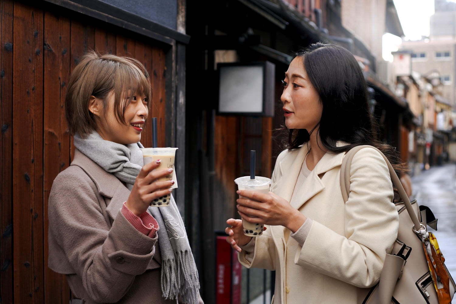 Mulhers conversando e segurando um copo de café.