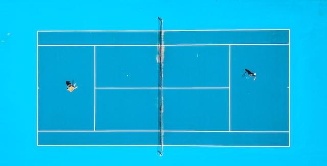 Quadra de tênis simples com fundo azul e dois tenistas