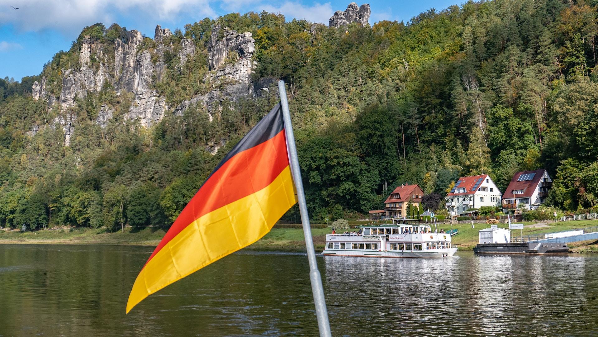 Fotografia da bandeira na Alemanha com fundo natural com rios e montanhas