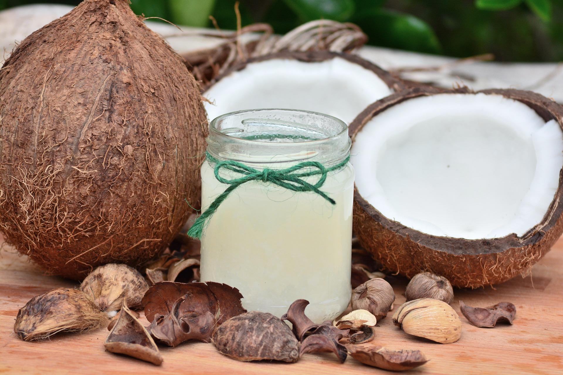 Imagem de um coco aberto e um pote de vidro com a água do coco ou o óleo do coco.