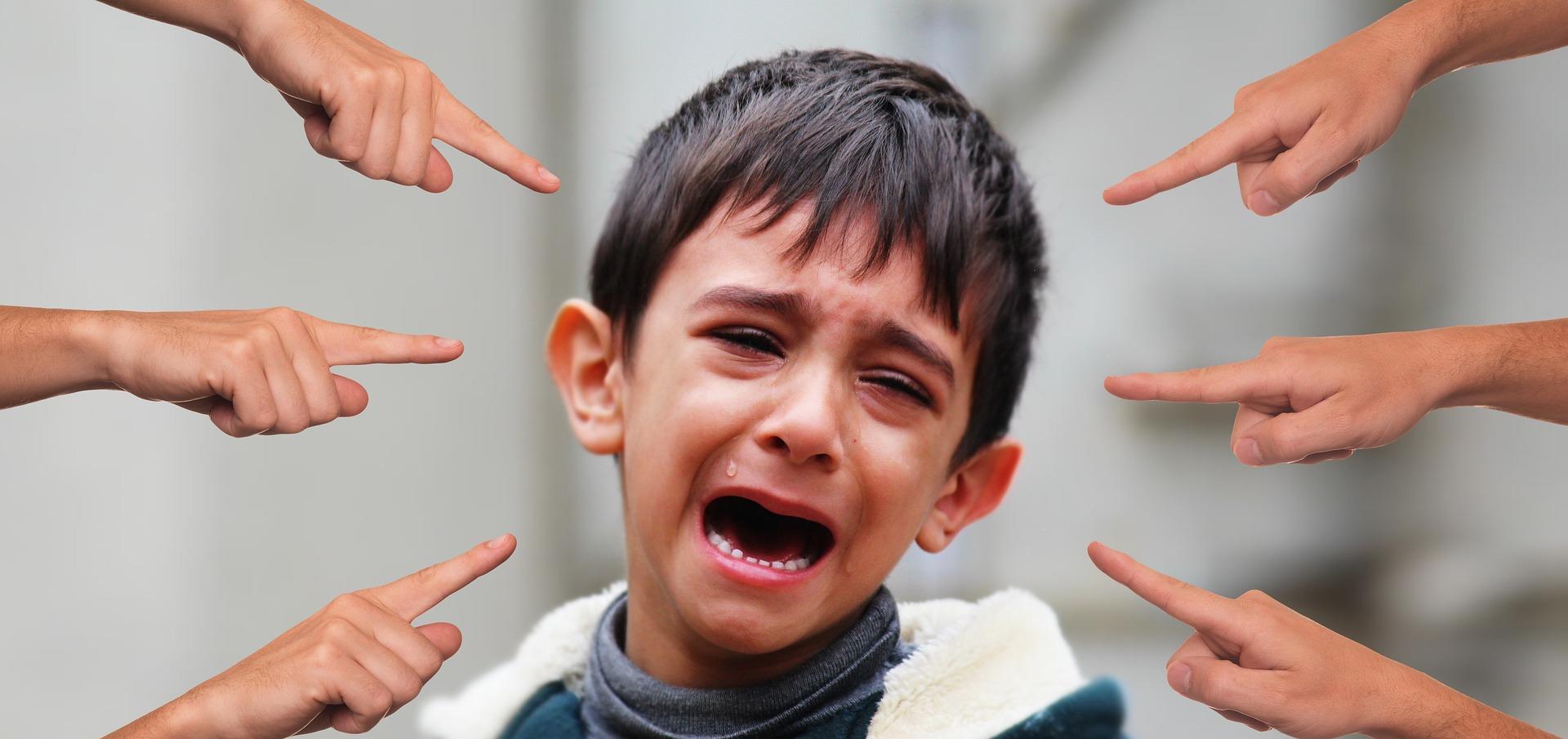Criança chorando e sendo apontada por dedos.