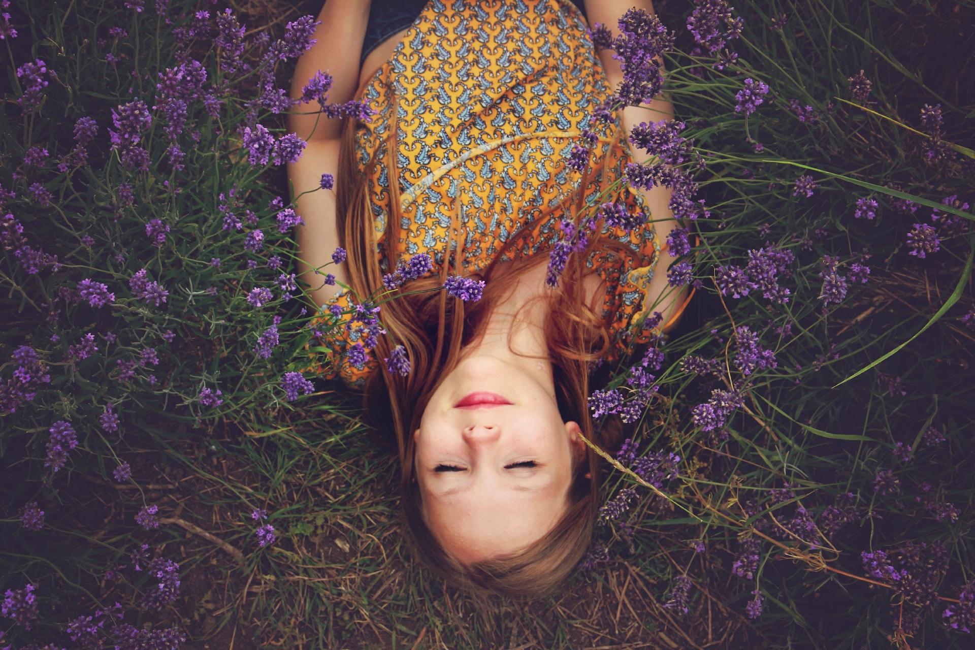 Criança deitada em um campo de lavanda com os olhos fechados.