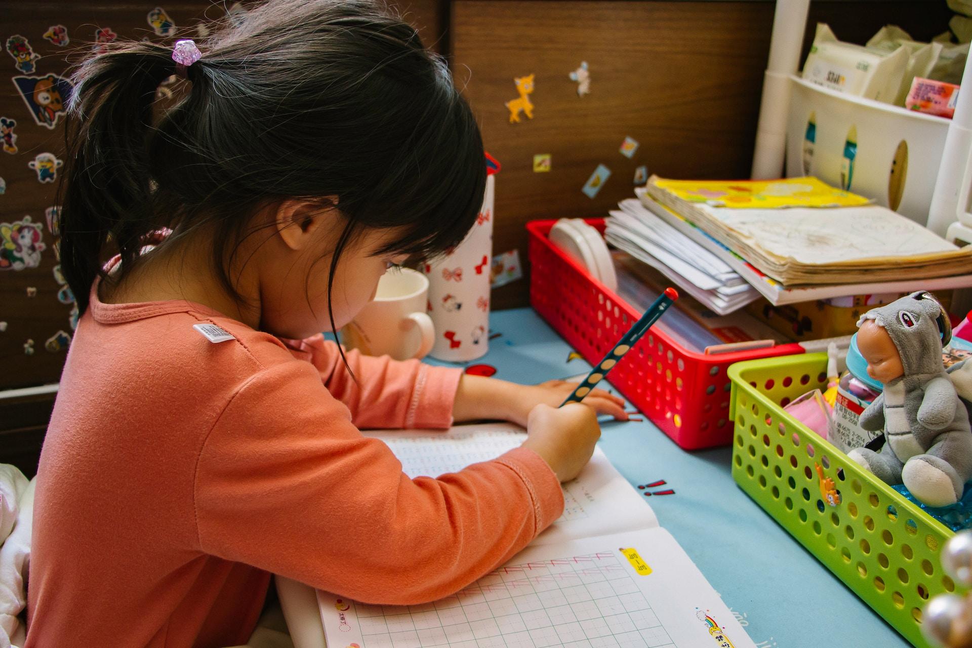 Criança estudando em uma mesa em casa