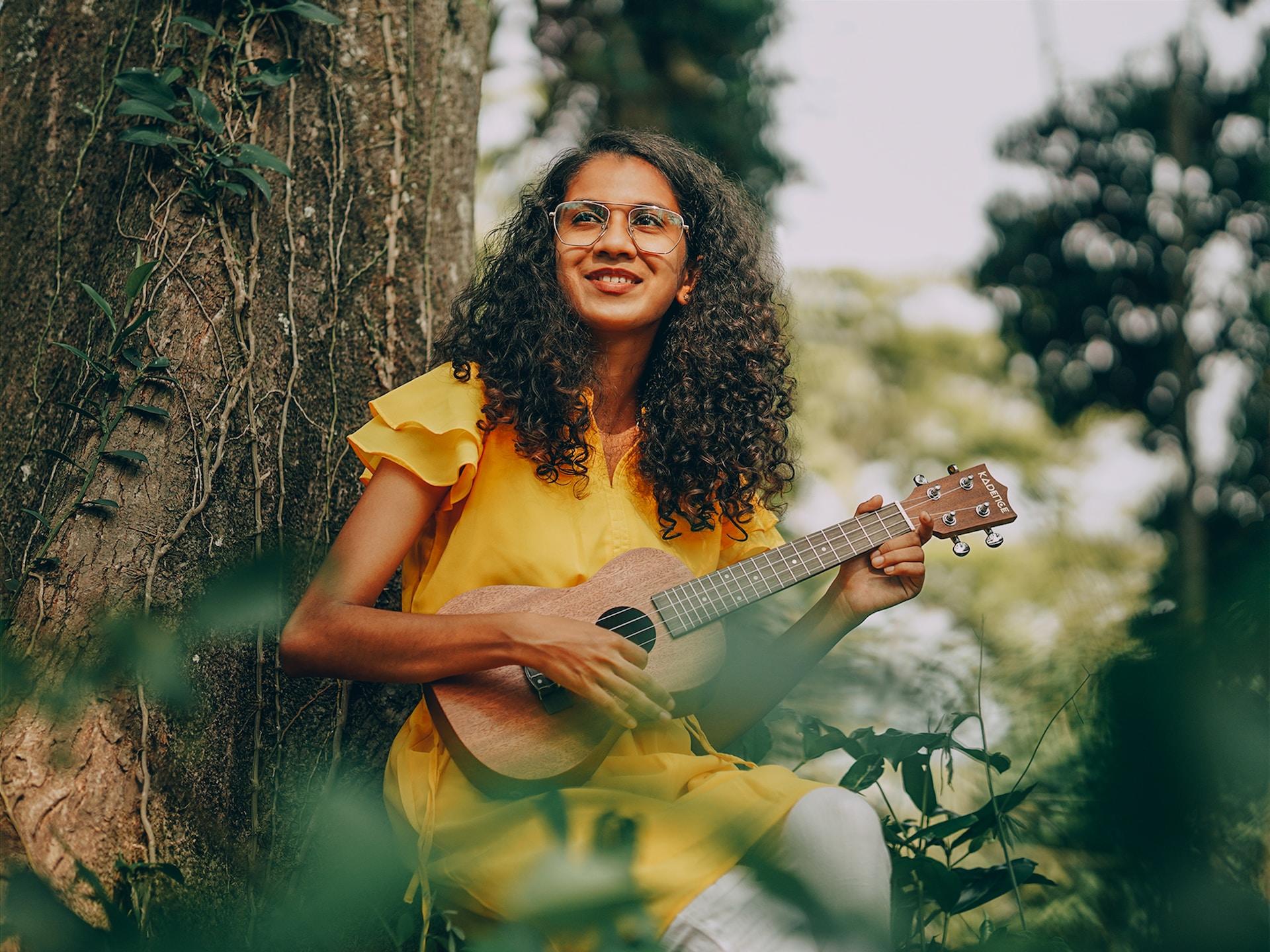 Fotogrrafia de mulher segurando cavaquinho em meio ás flores