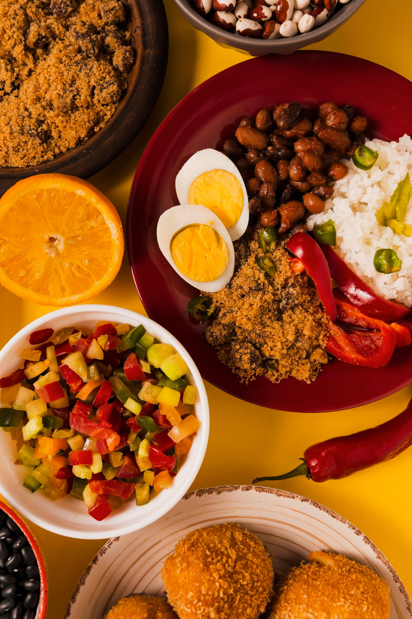 Feijoada, laranja, salada, farofa, arroz, acarajé e outras comidas brasileiras nos pratos em cima da mesa.