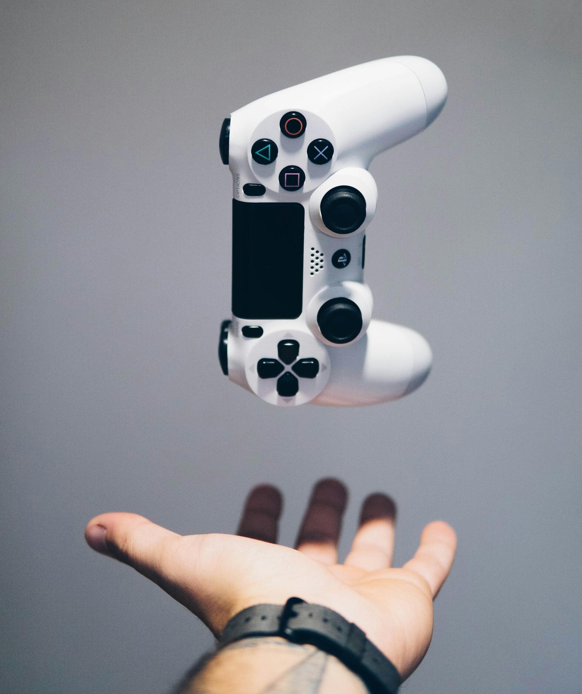 Imagem de um controle de videogame e uma mão.