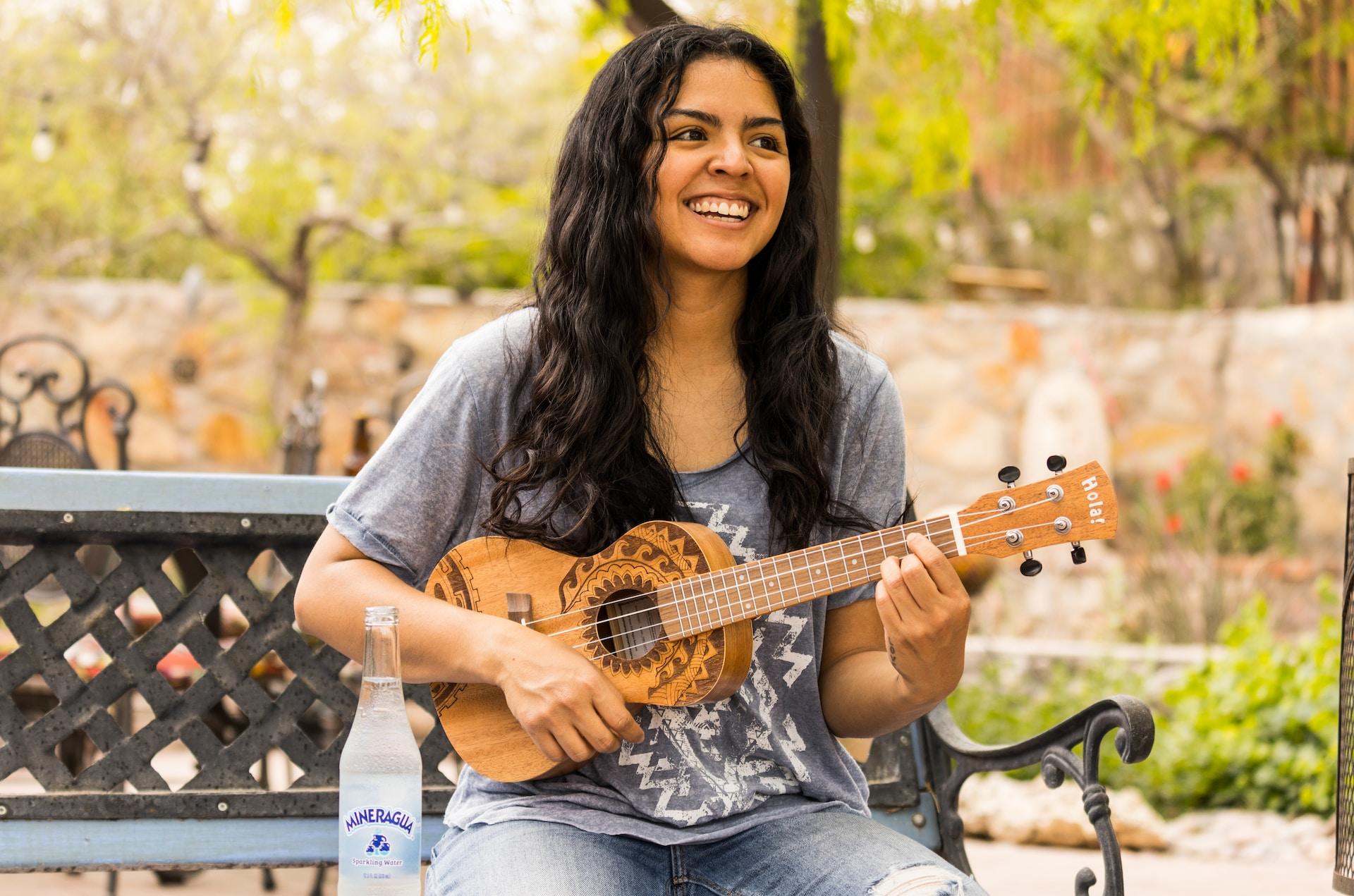Mulher tocando cavaquinho em frente a plantas