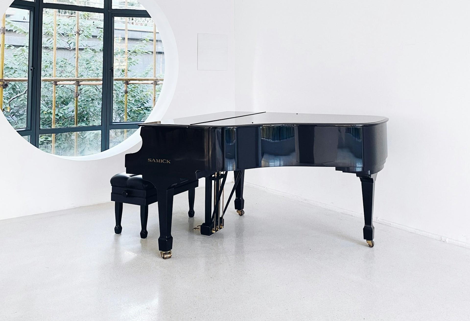 Piano de calda preto em uma sala branca.