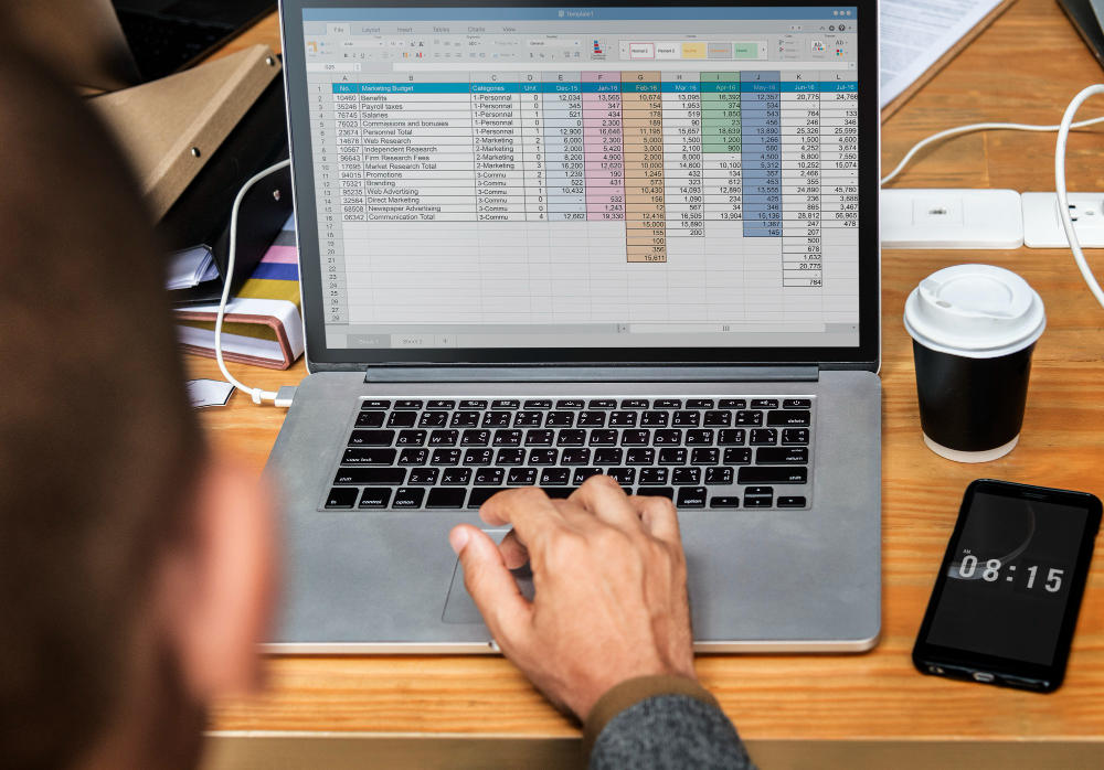 Fotografia com mão masculina mexendo em computador enquanto monta planilha Excel