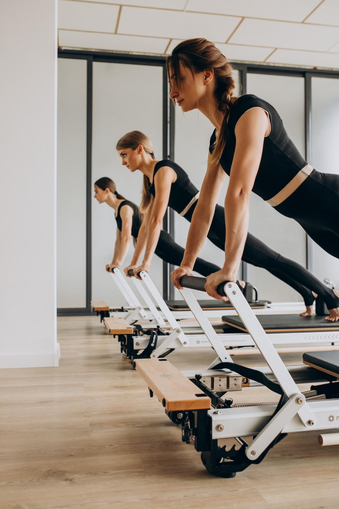 Alunas fazendo exercícios nas máquinas de pilates.
