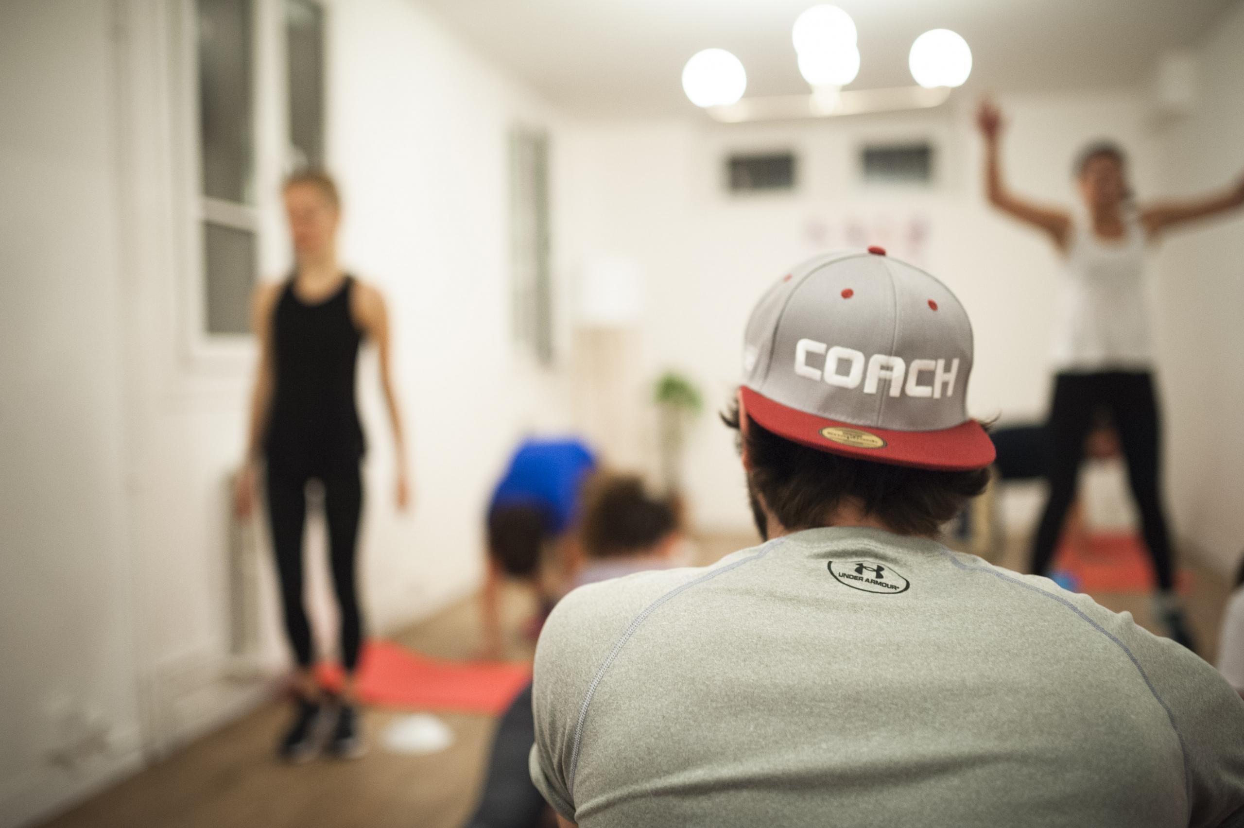Homem com o boné escrito coch dando aula de gisnática