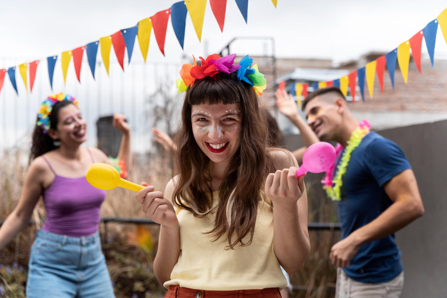 Trio dançando com bandeirinhas de carnaval.