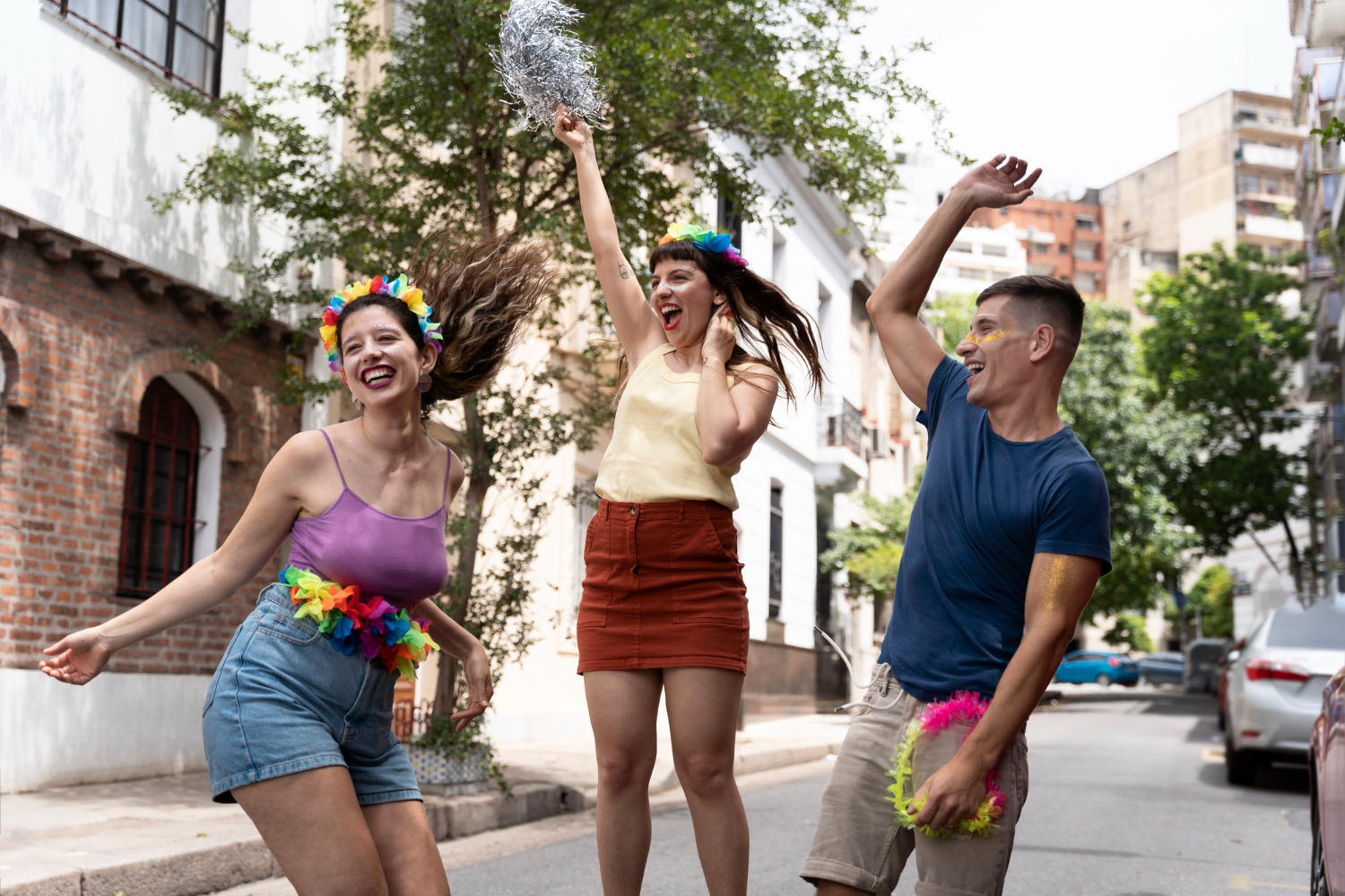 Três amigos dançando no carnaval no meio da rua.