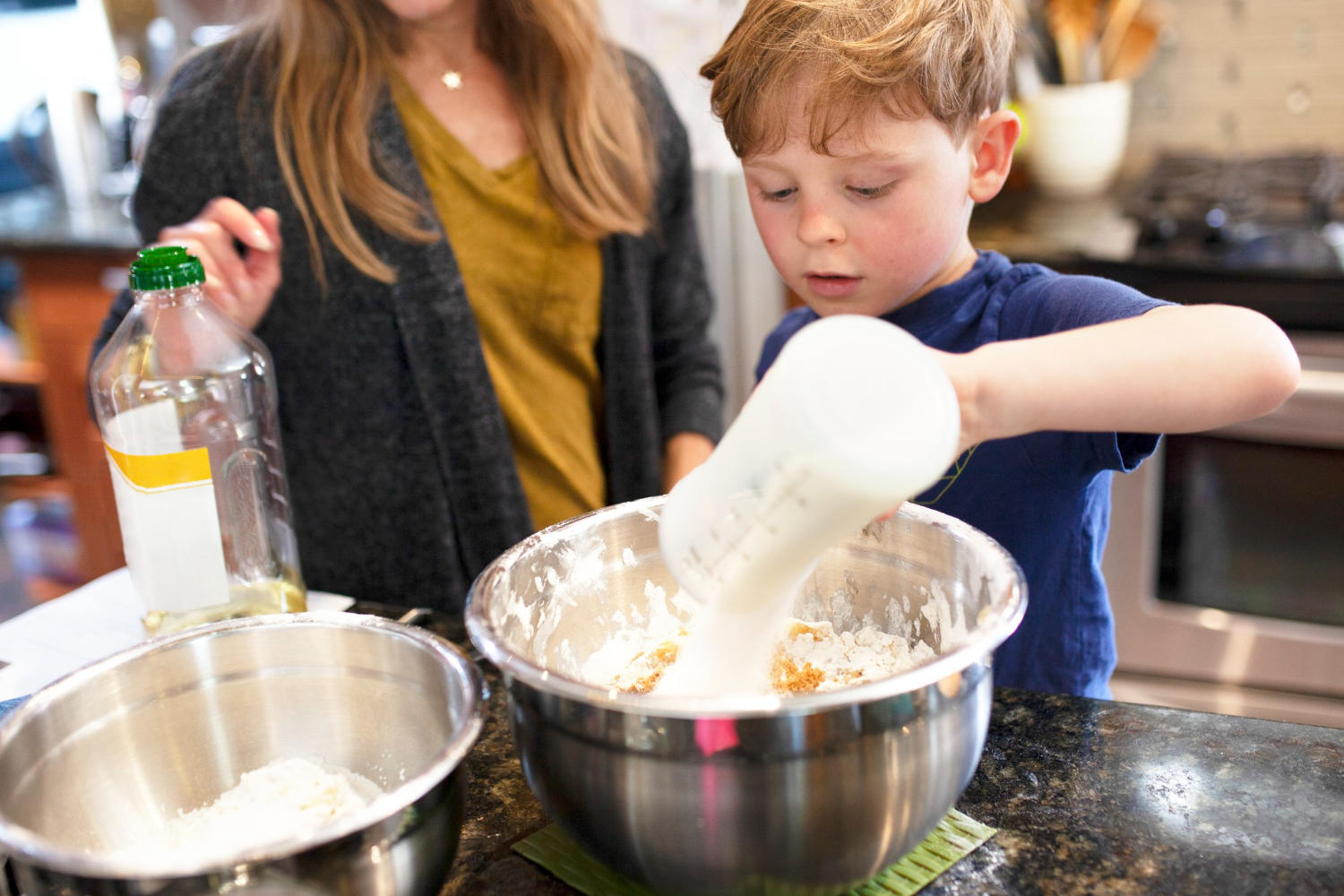 Criança e adulto preparando massa na cozinha.