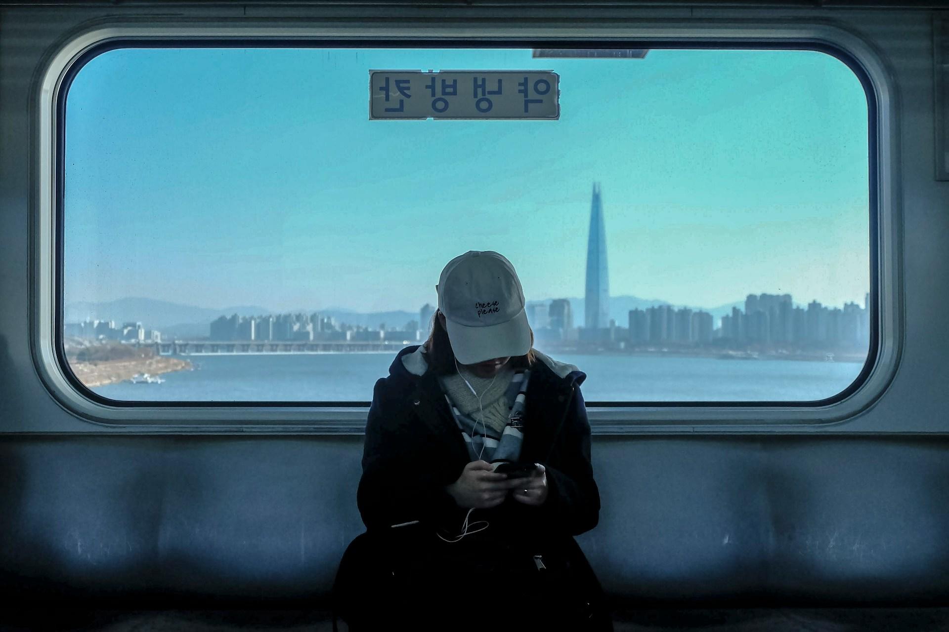 Mulher em um metrô da Coreia usando um celular