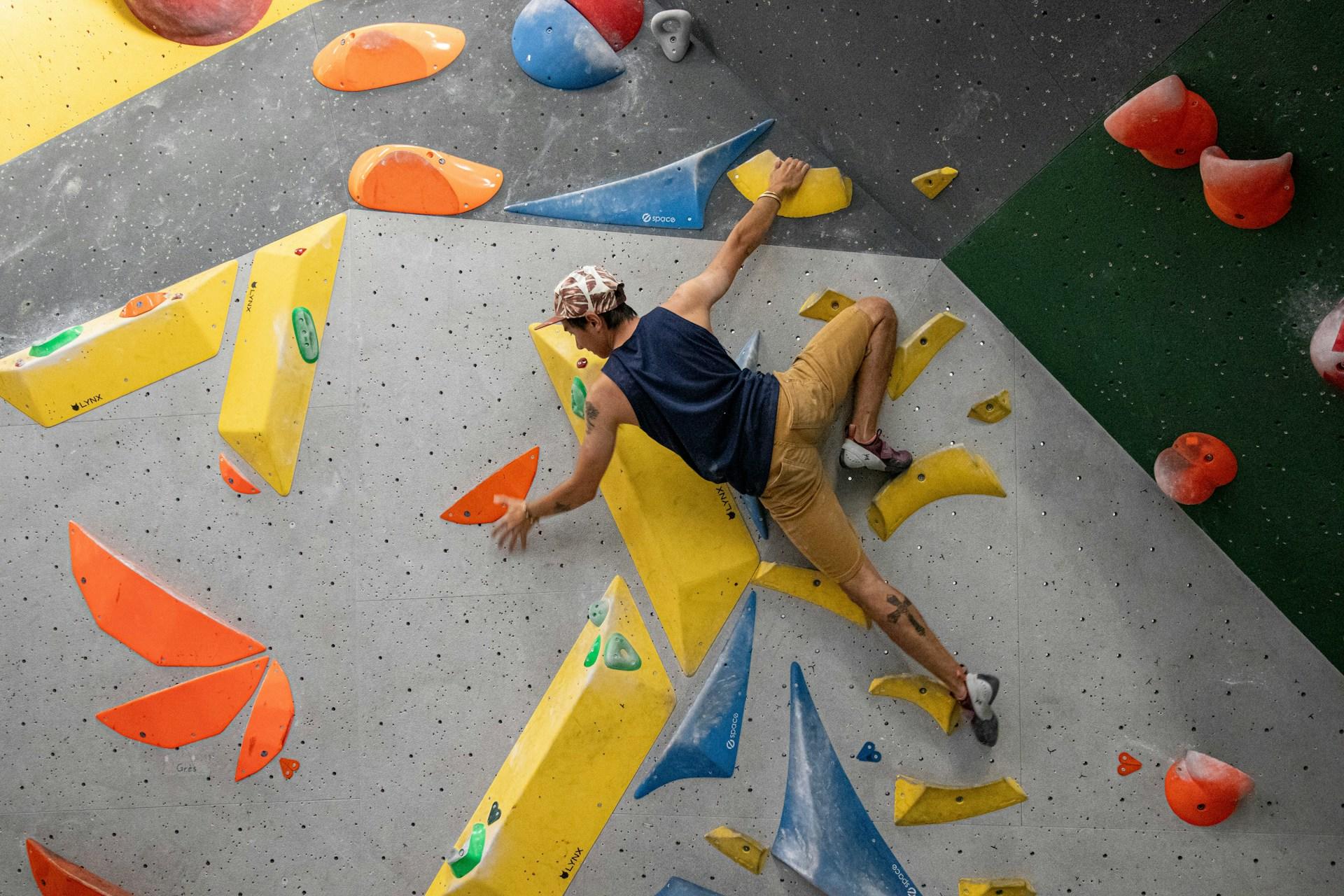 Homem subindo em uma parede de escalada.