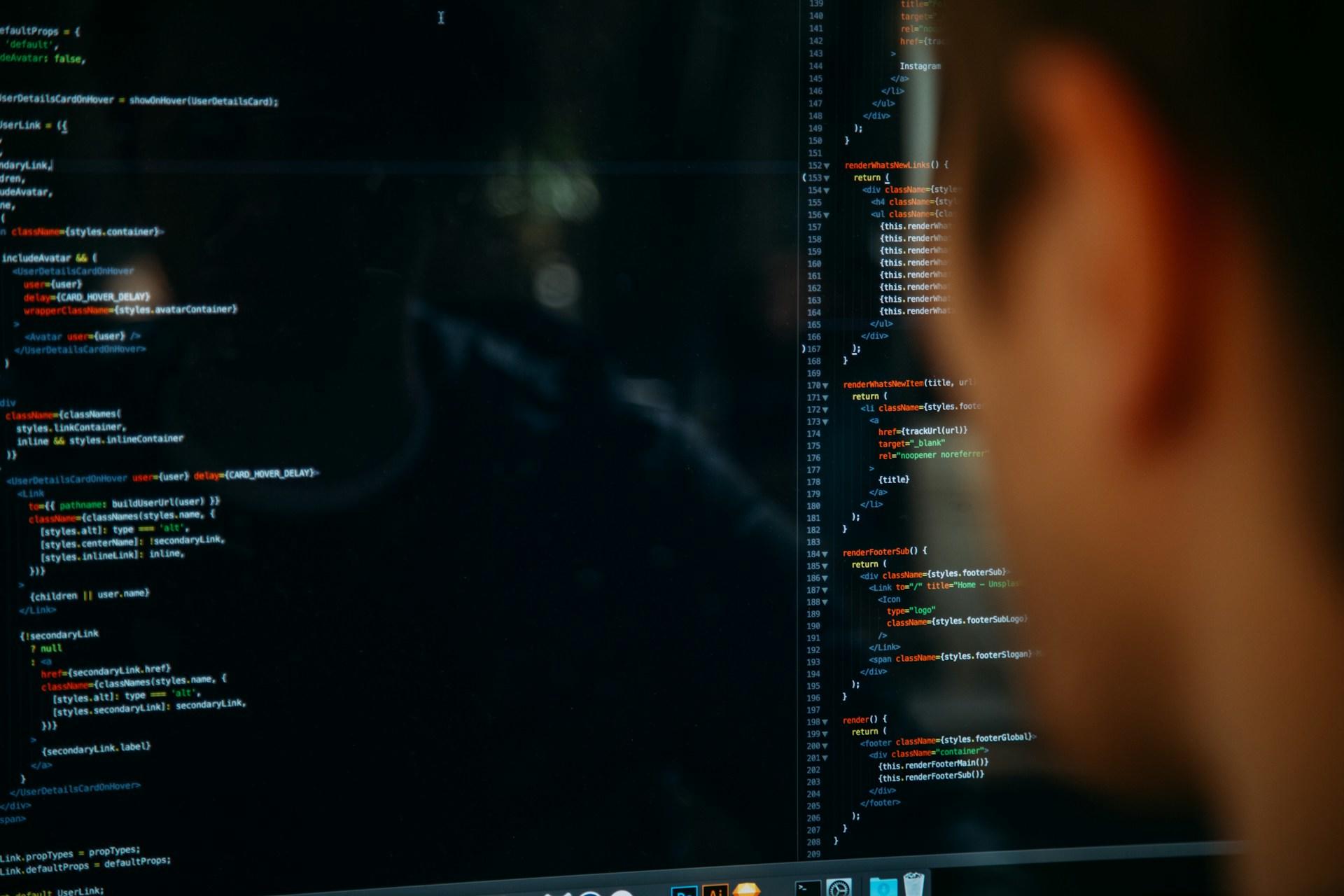 Imagem desfocada de um homem olhando para uma tela de computador com códigos de programação.