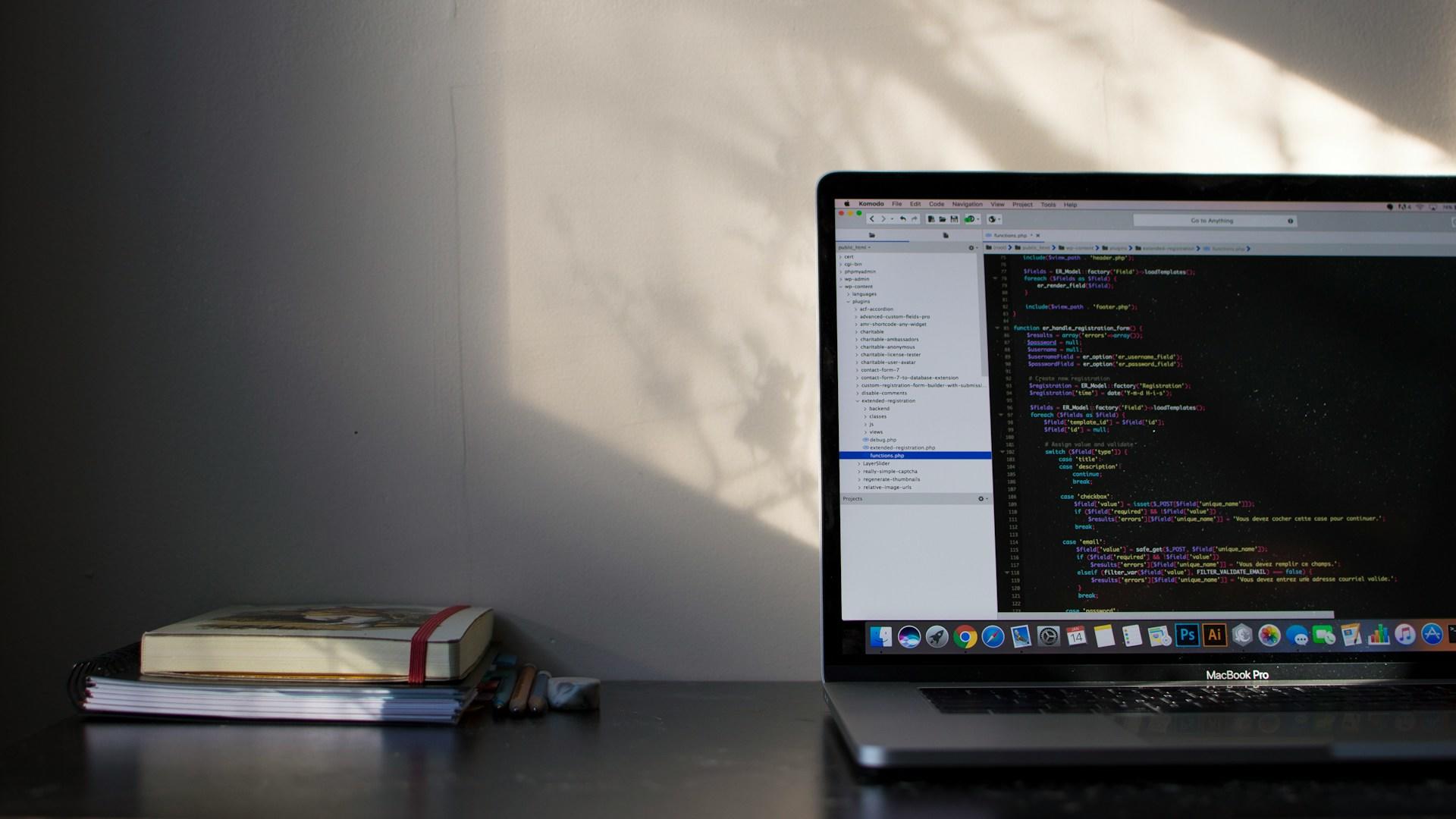 Livros e um computador com códigos de programação na tela. 
