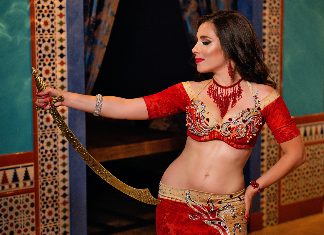 dançarina de vermelho e trajes de dança do ventre segurando uma espada de dança