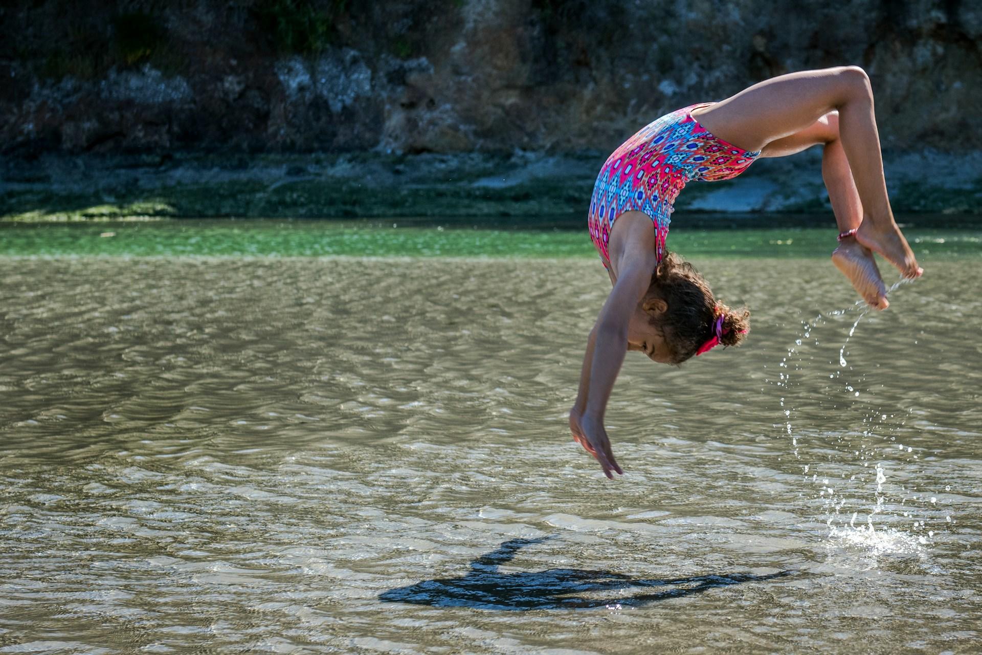 Menina fazendo acrobacia em uma praia.