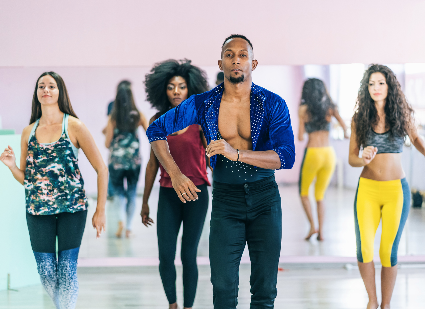 dançarino de salsa ao centro com outras alunas aprendendo atrás