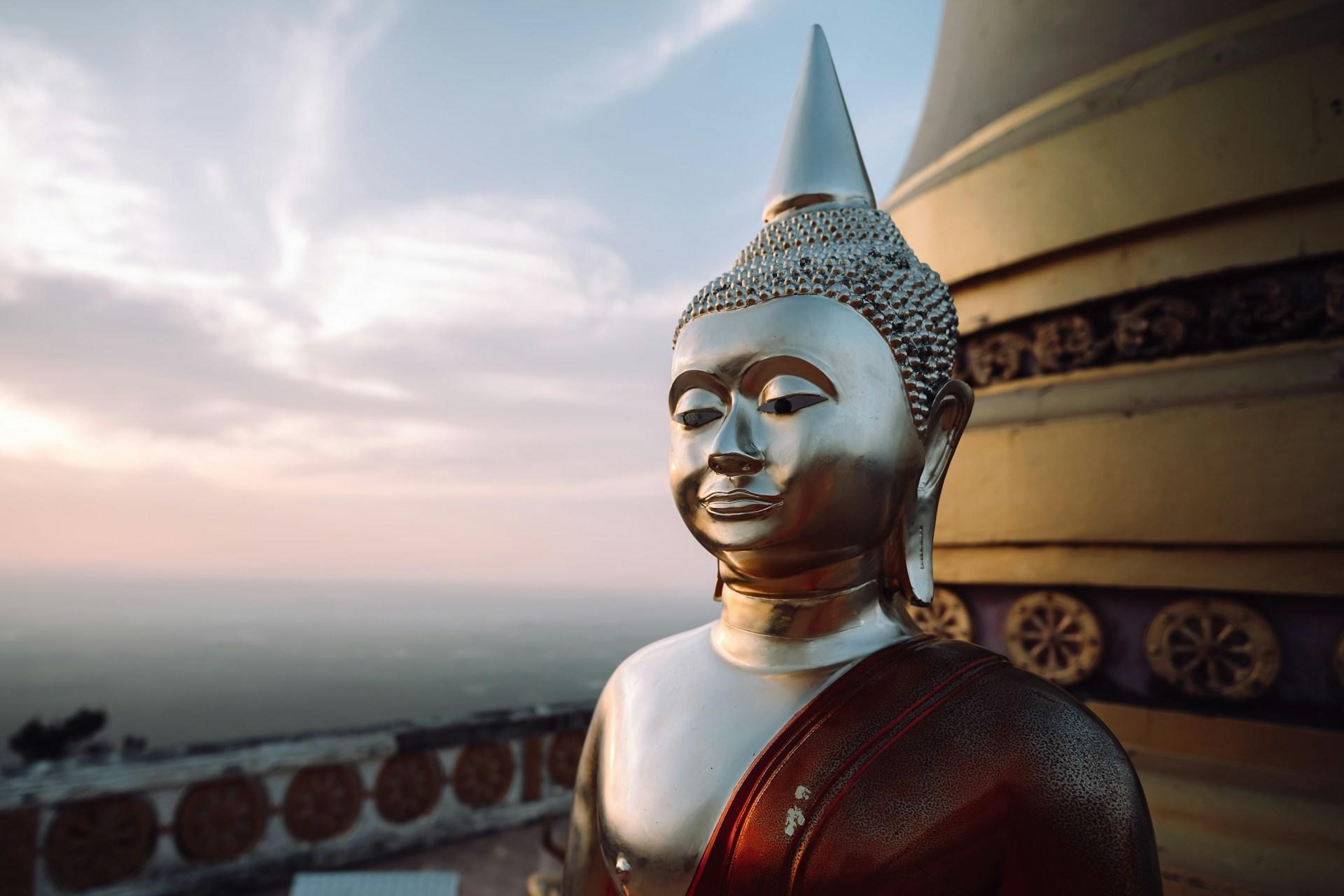 Imagem do buda em prata no alto d euma torre
