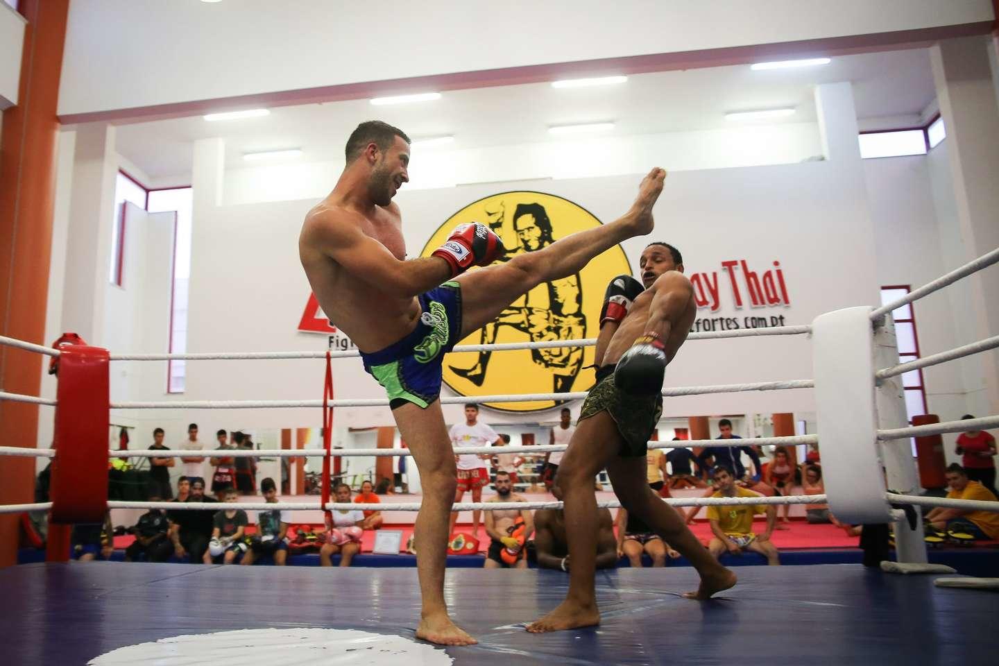 Duas pessoas lutando e treinando muay thai em academia especializada