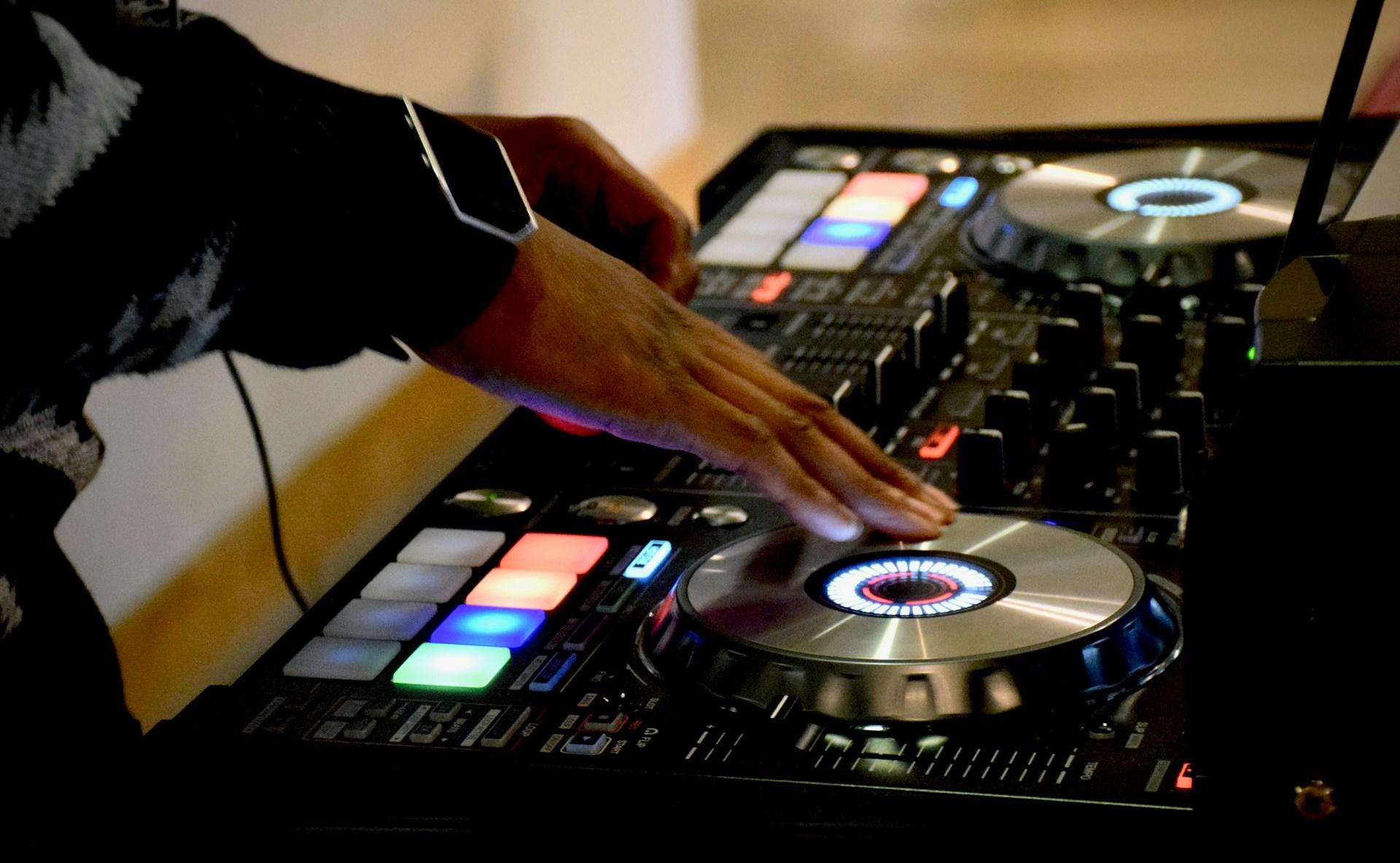 Imagem de uma mesa de som de DJ com duas mãos tocando