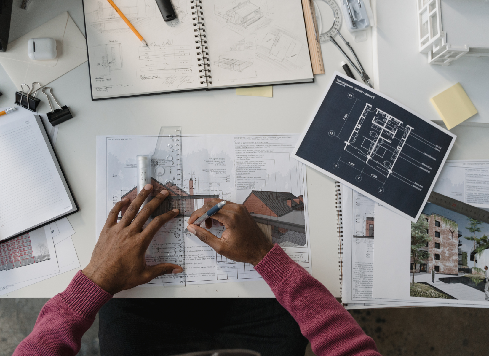 Mãos em uma mesa com vários objetos arquitetônicos em volta