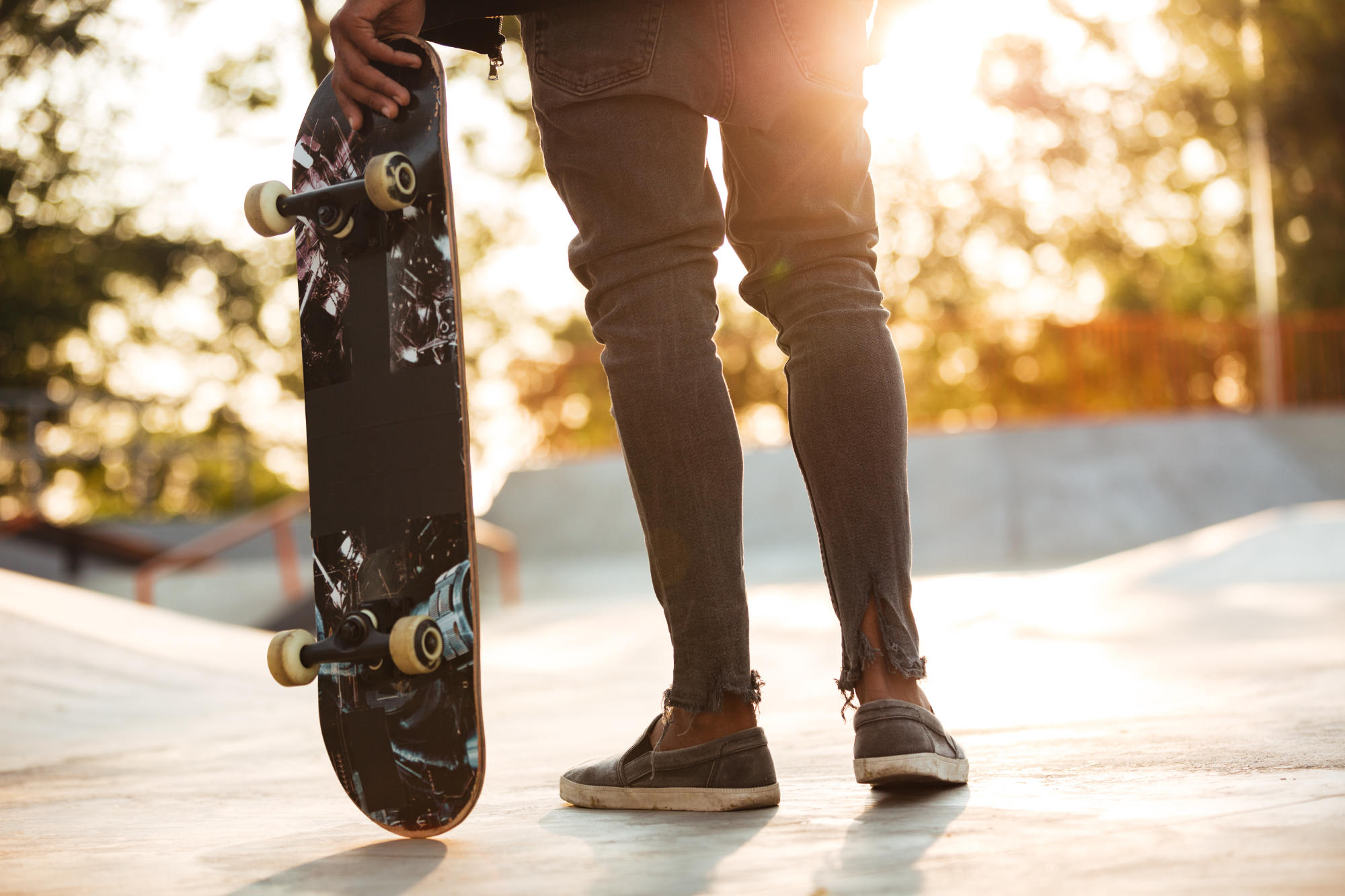 Homem segurando um skate na pista.
