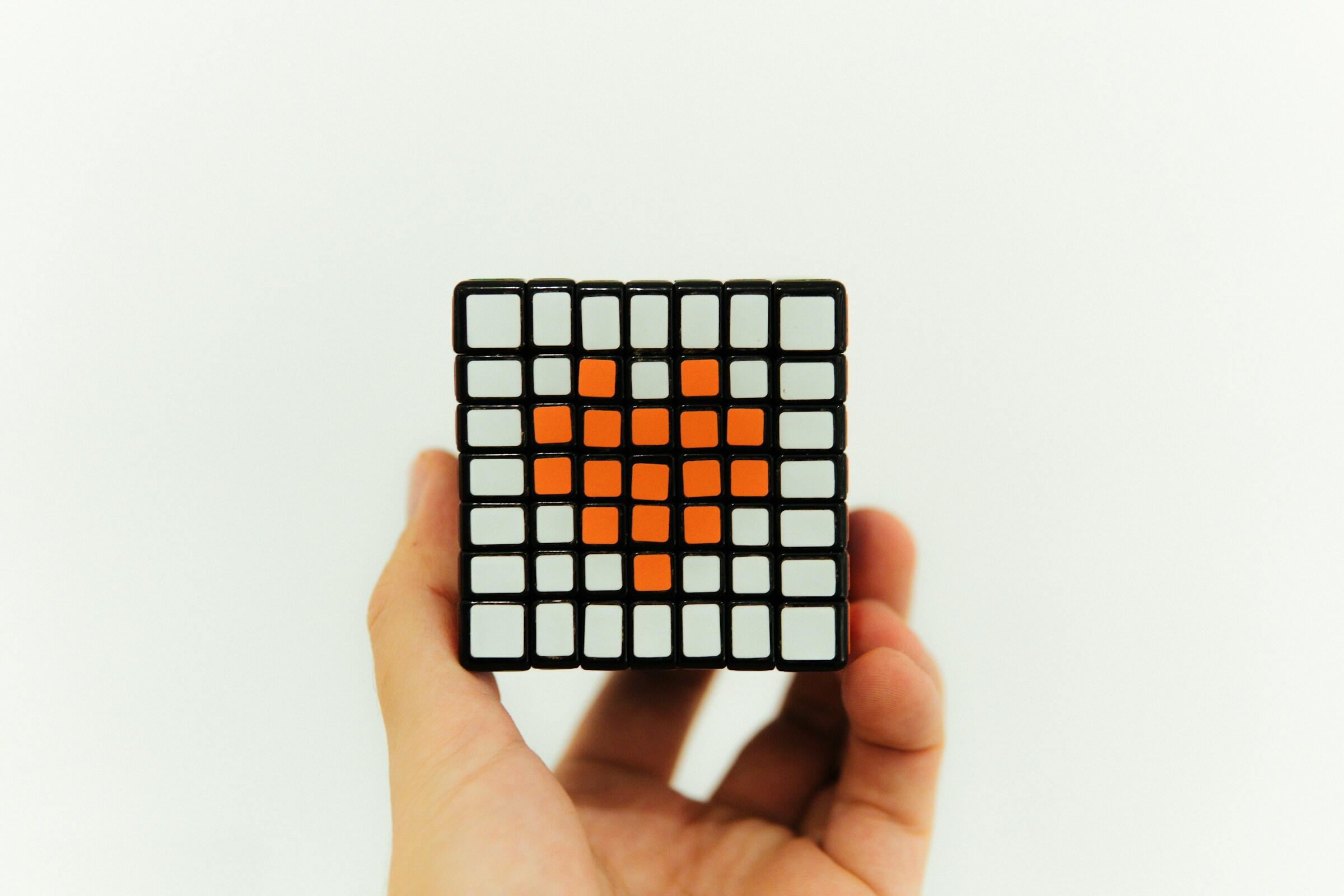 cubo magico em uma mão centralizada com um coração na parte dos cubos