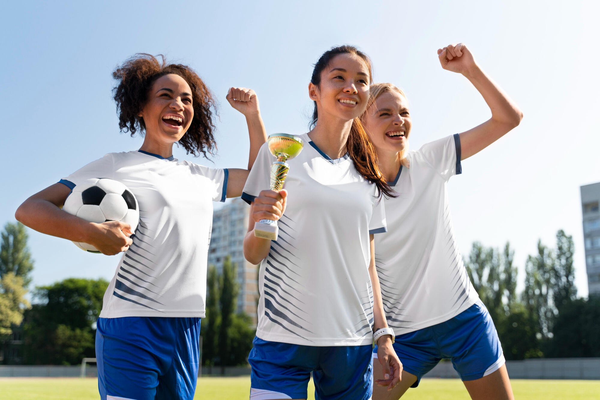 Jogadoras de futebol, comemorando o troféu.