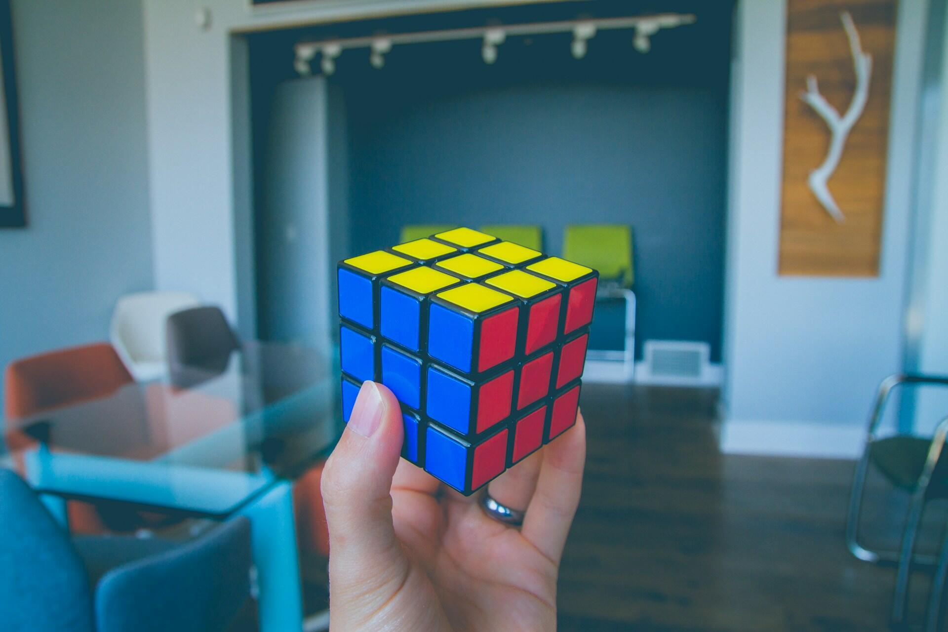 Uma mão segurando um cubo rukib em uma sala vazia