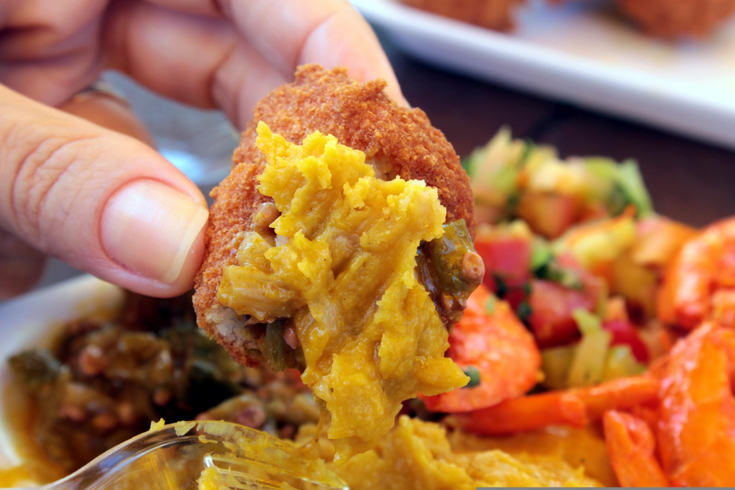 Pedaço de acarajé na mão da pessoa.