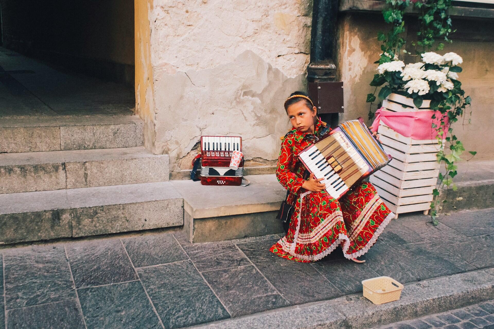 Menina sentada na calçada enquanto toca música espanhola