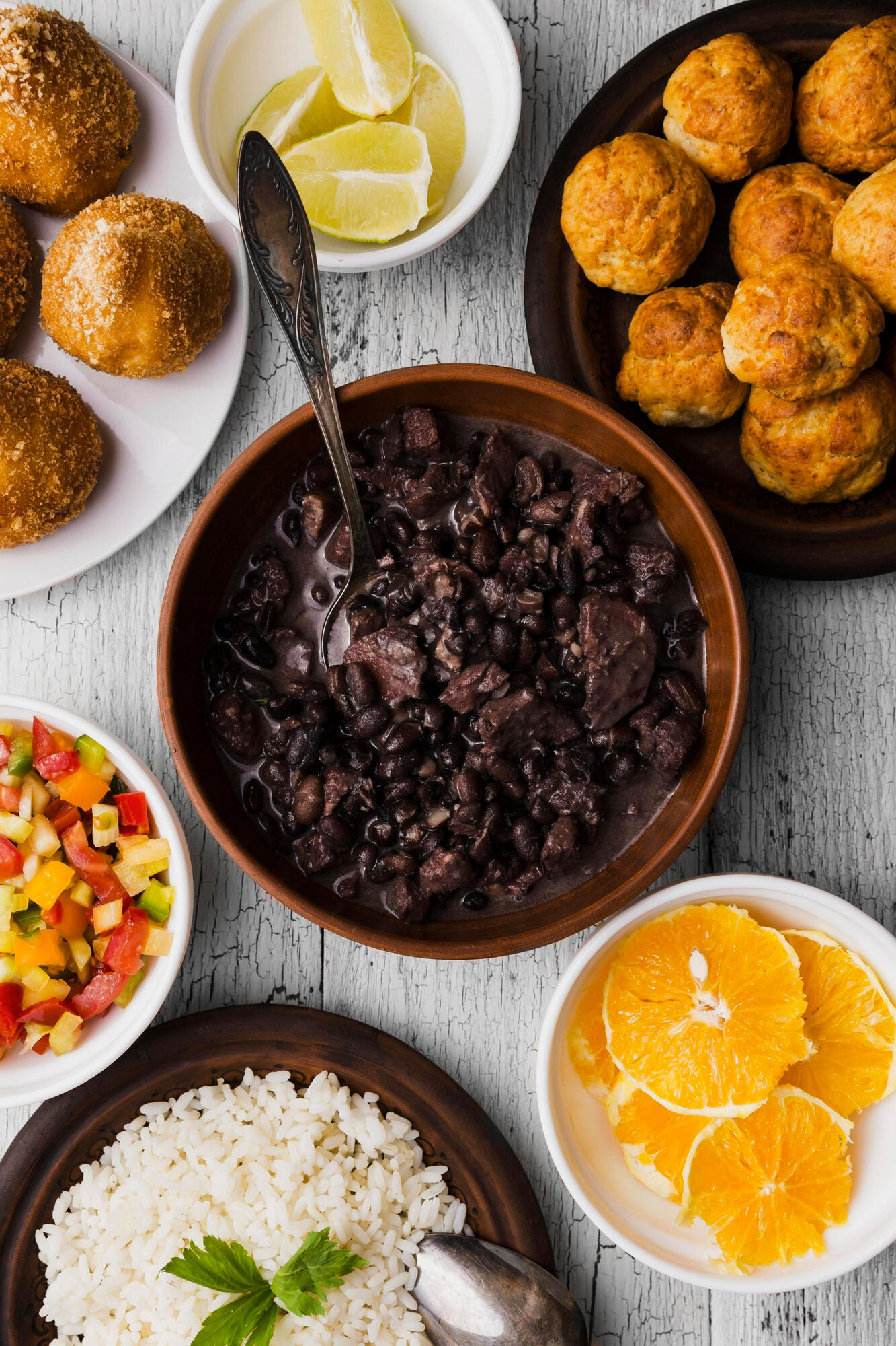 Feijoada com laranja, farofa, arroz e petiscos em cima da mesa.