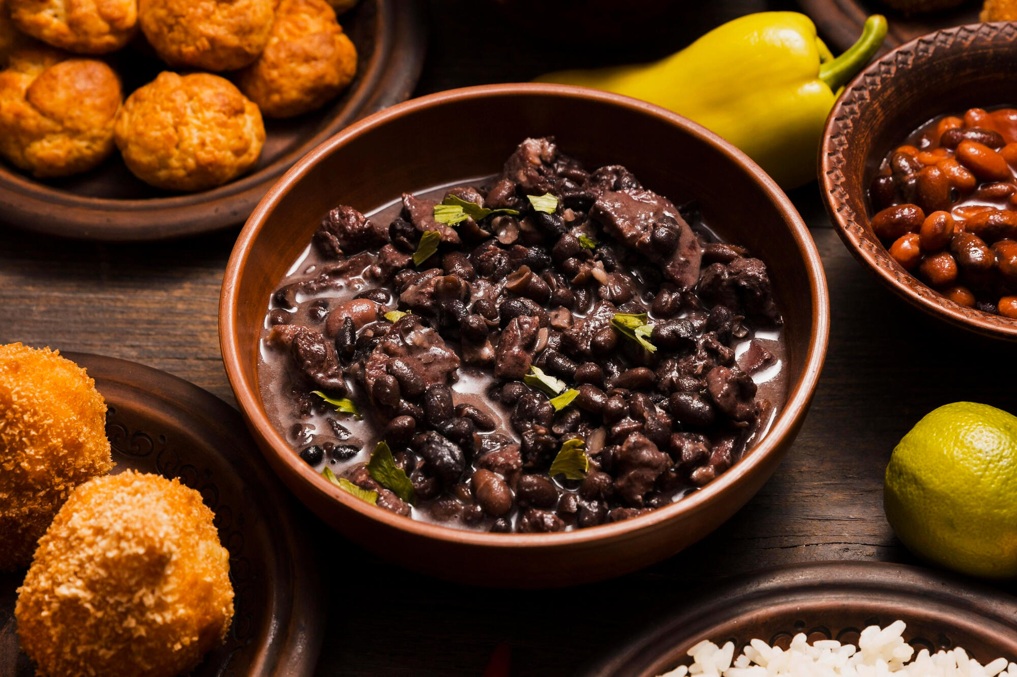 Feijão com bolinhos e legumes ao redor.