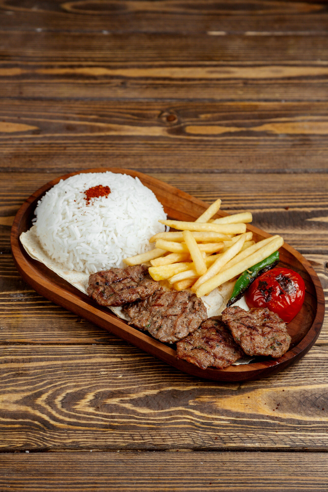 Carne, arroz, batata fritas e legumes em cima do prato.