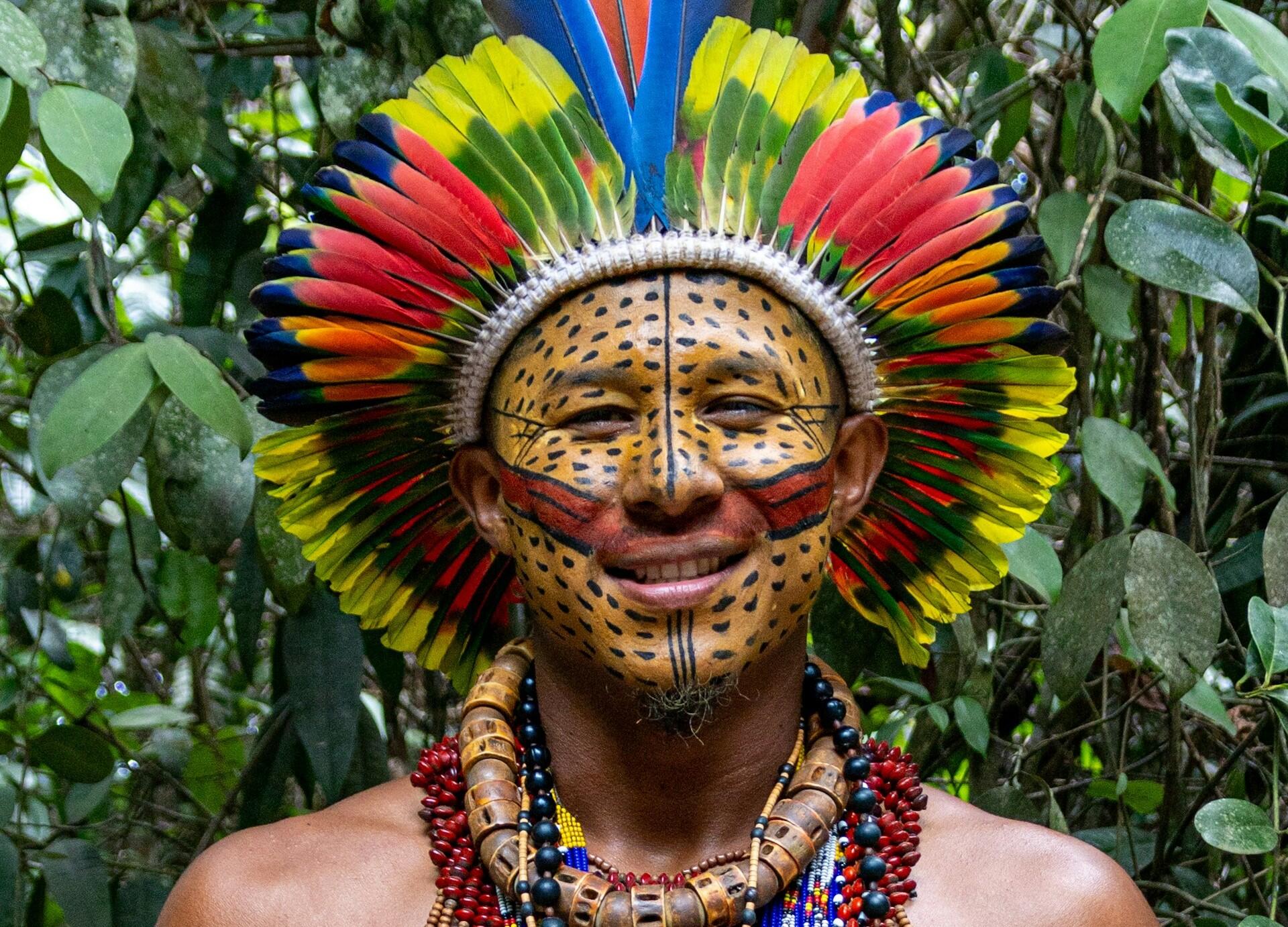Homem indígena com um cocar e a cara pintada