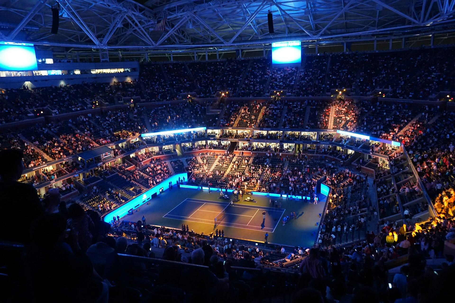 Imagem de um jogo de tênis em uma quadra fechada