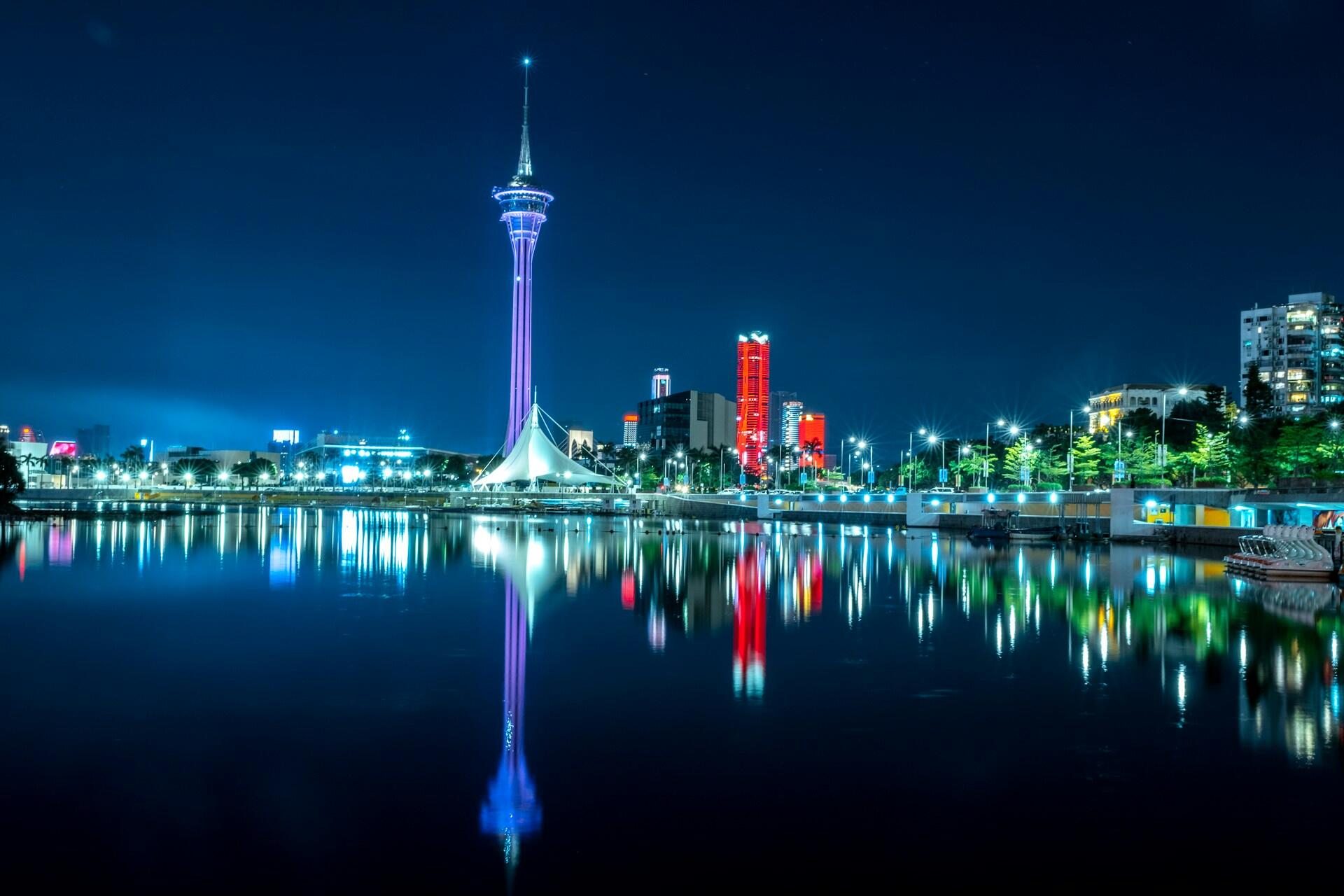 Imagem de Macau durante a noite, com luzes coloridas.