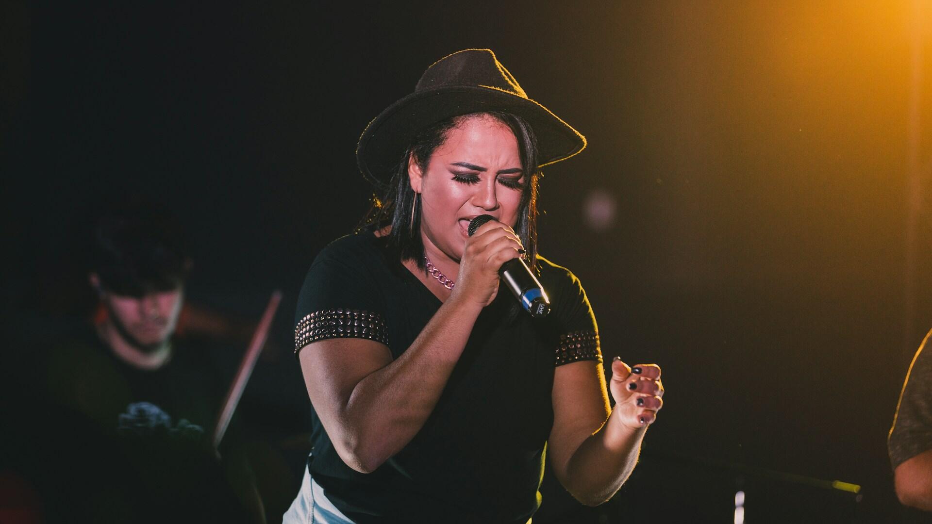 Mulher cantando em um palco de chapéu