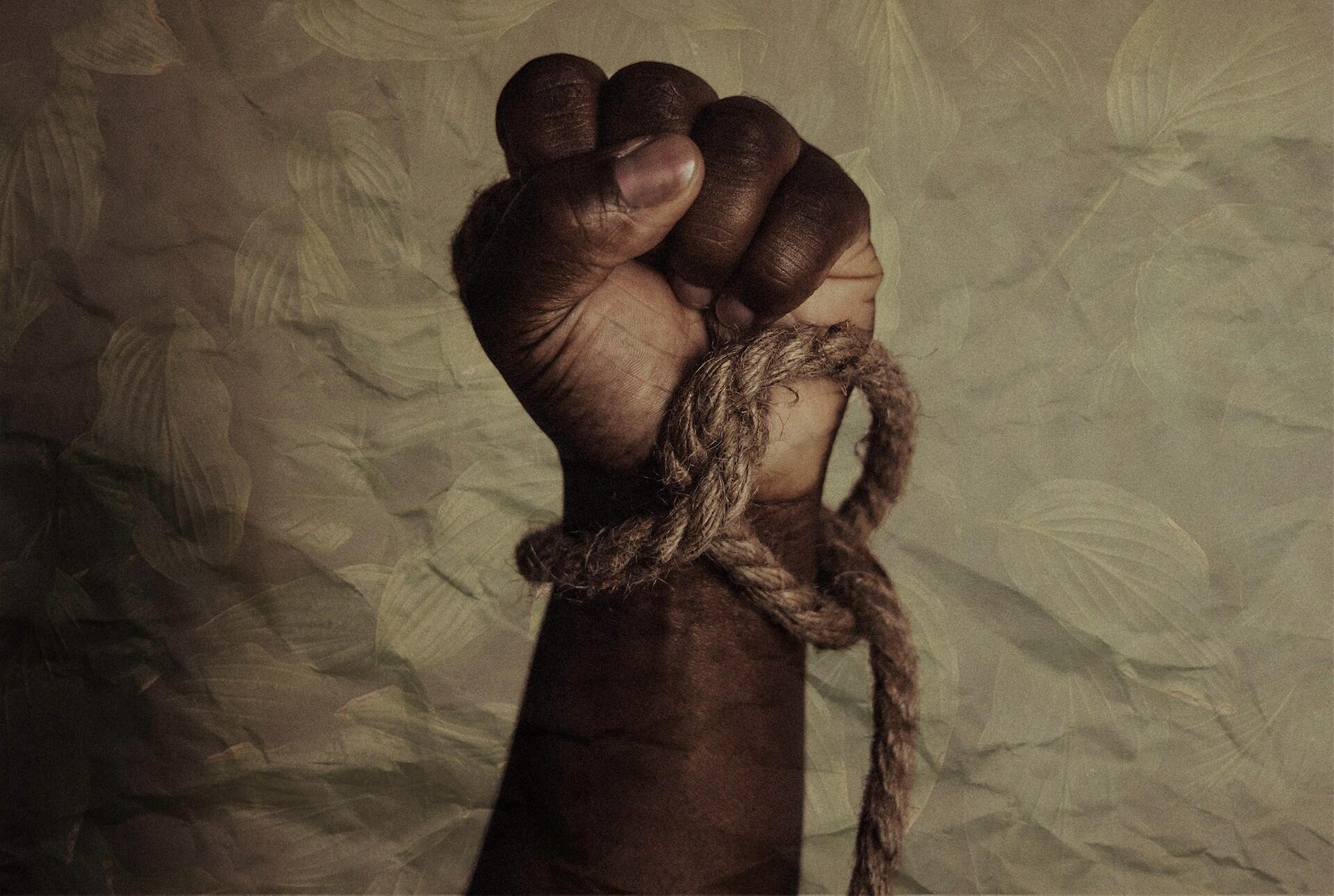 Imagem de uma mão negra com uma corda amarrada