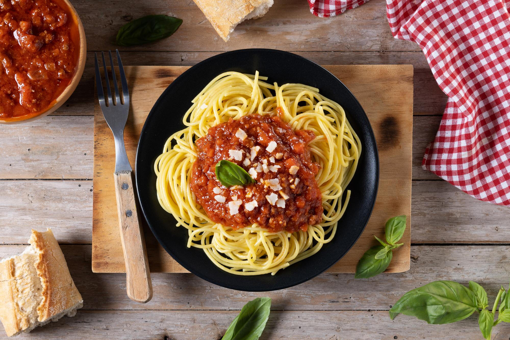 Macarrão a bolonhesa no prato em cima da mesa.
