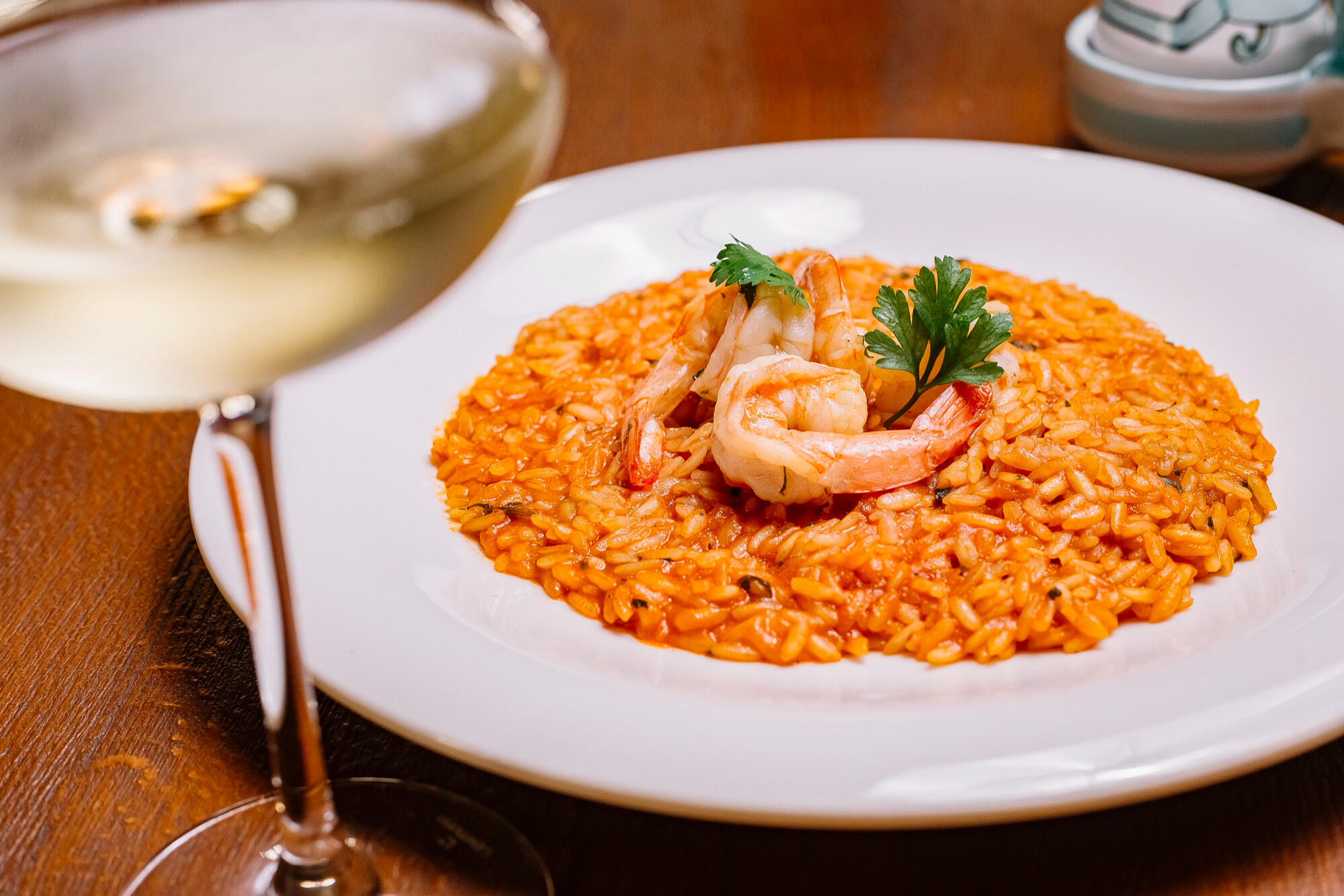 Risoto de camarão no prato em cima da mesa, e vinho.